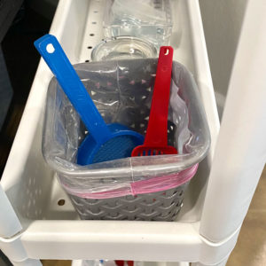 two small plastic litter box scoops stored in plastic lined container