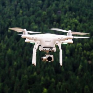 white drone flying over trees