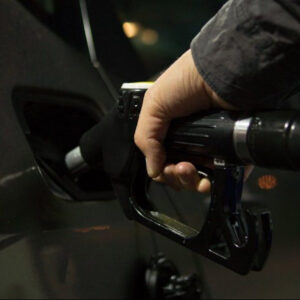 close up on hand holding gas pump handle and putting gas into car