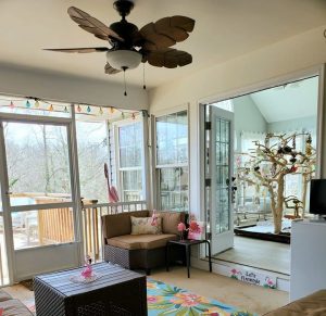 screened in porch with furniture and ceiling fan that is next to the bird room
