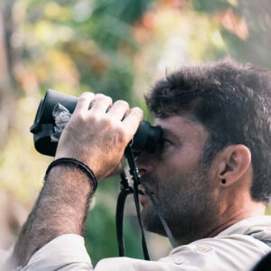 close up on man holding binoculars up to eyes