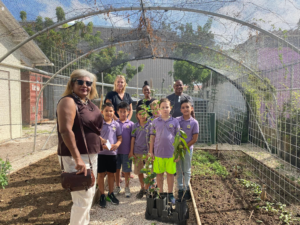 a group of children and adults pose for a photo in a native plant nursery