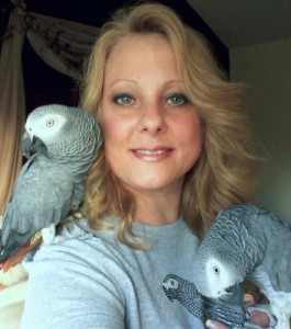 head shot of Lisa Bono with African grey parrot on either shoulder