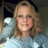 head shot of Lisa Bono with African grey parrot on either shoulder