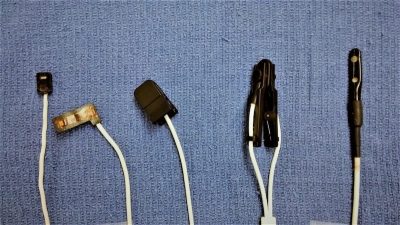 Pulse-oximeter probes. From left to right: flat reflectance probe, flat wrap probe, small clip probe, large clip probe, flat reflectance (rectal) probe